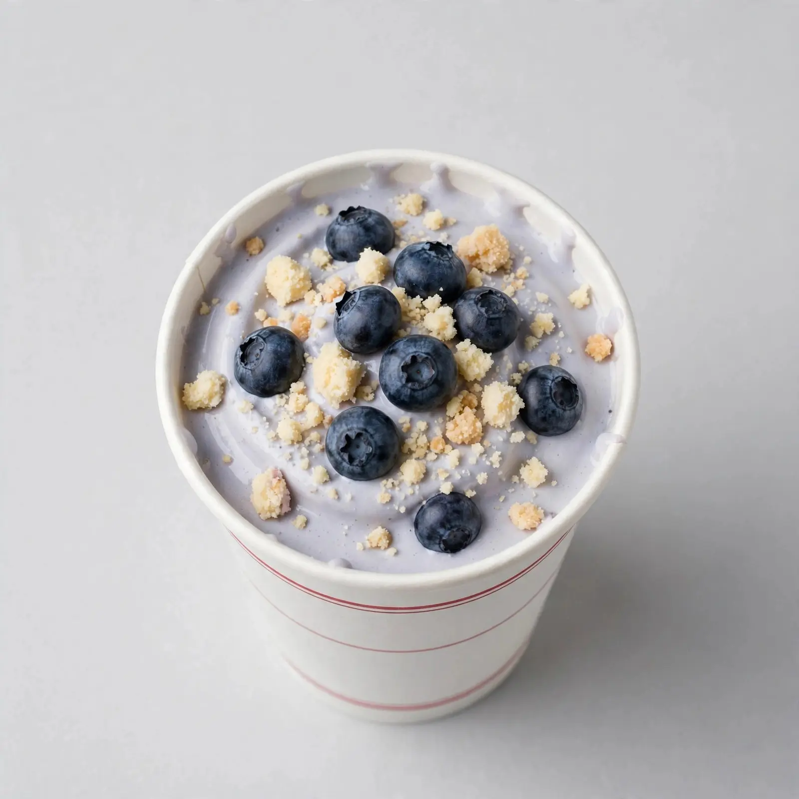 Blueberry cheesecake milkshake in a white cup topped with blueberries