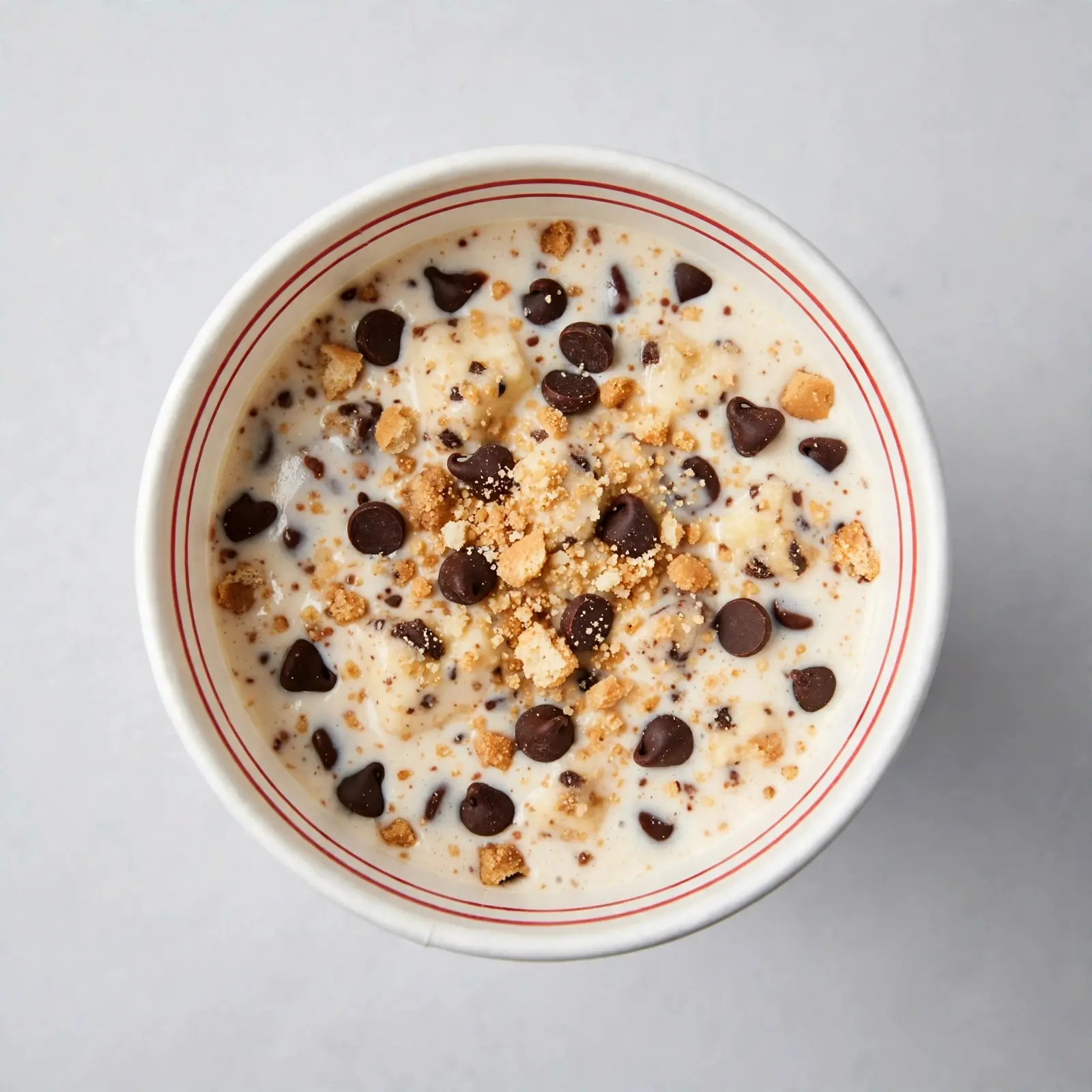 Chocolate chip cheesecake milkshake in a white cup topped with chocolate chips