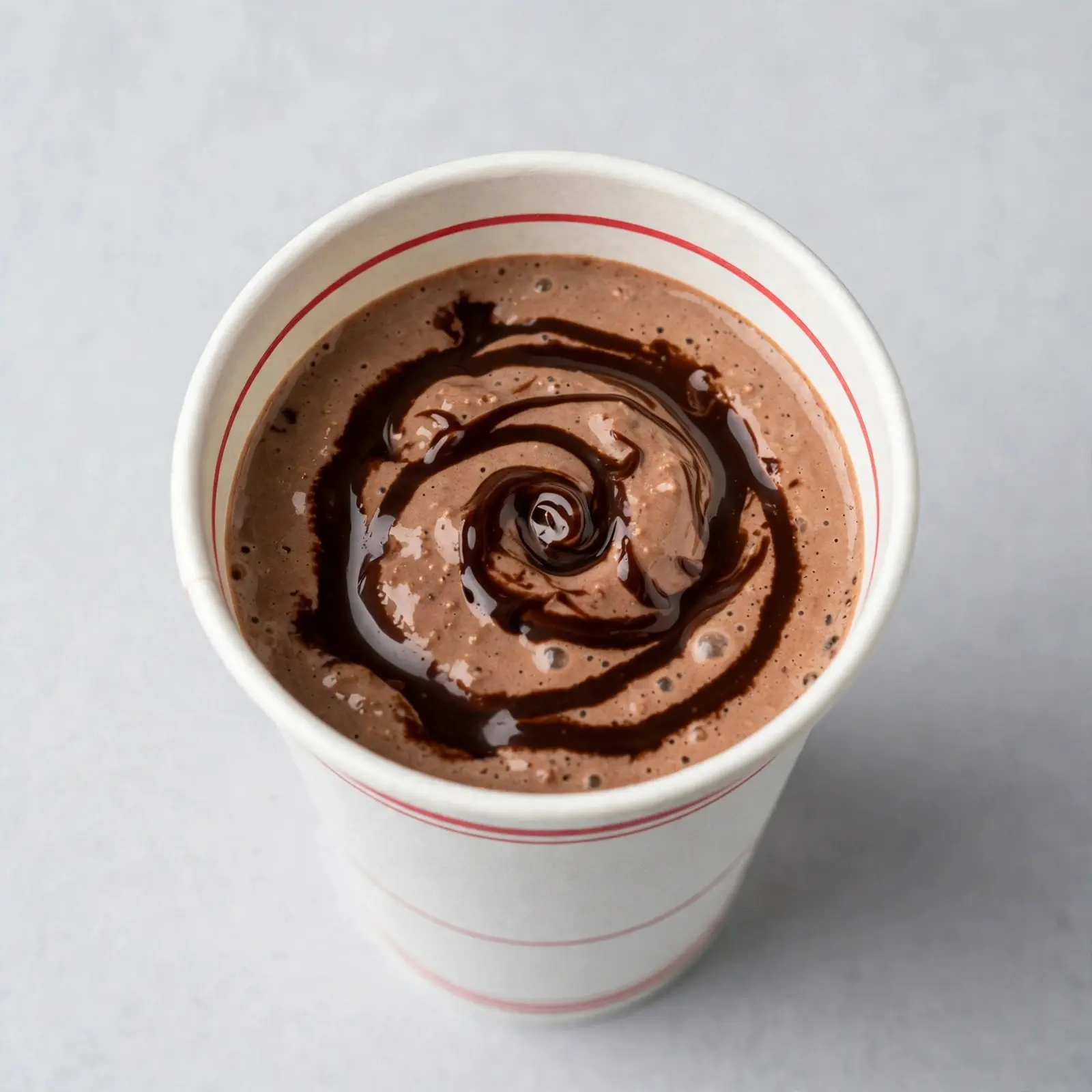 Creamy chocolate milkshake in a white cup with chocolate drizzle