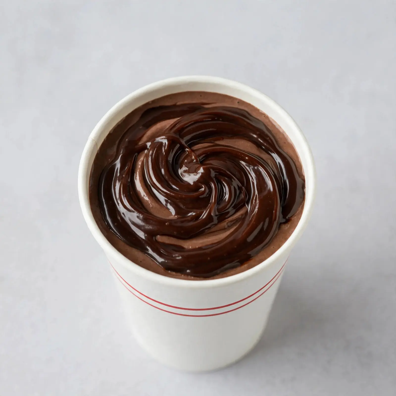Rich chocolate fudge milkshake in a white cup with fudge swirl