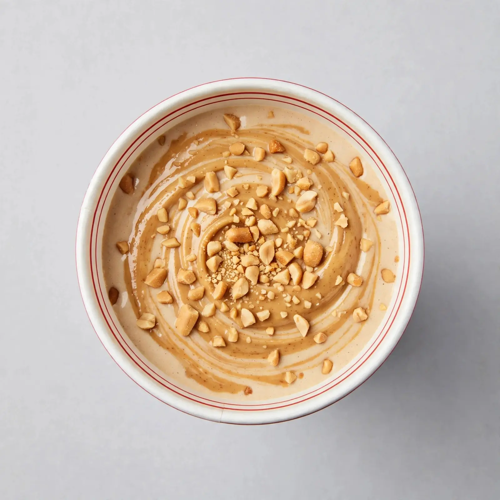 Creamy peanut butter milkshake in a white cup topped with crushed peanuts